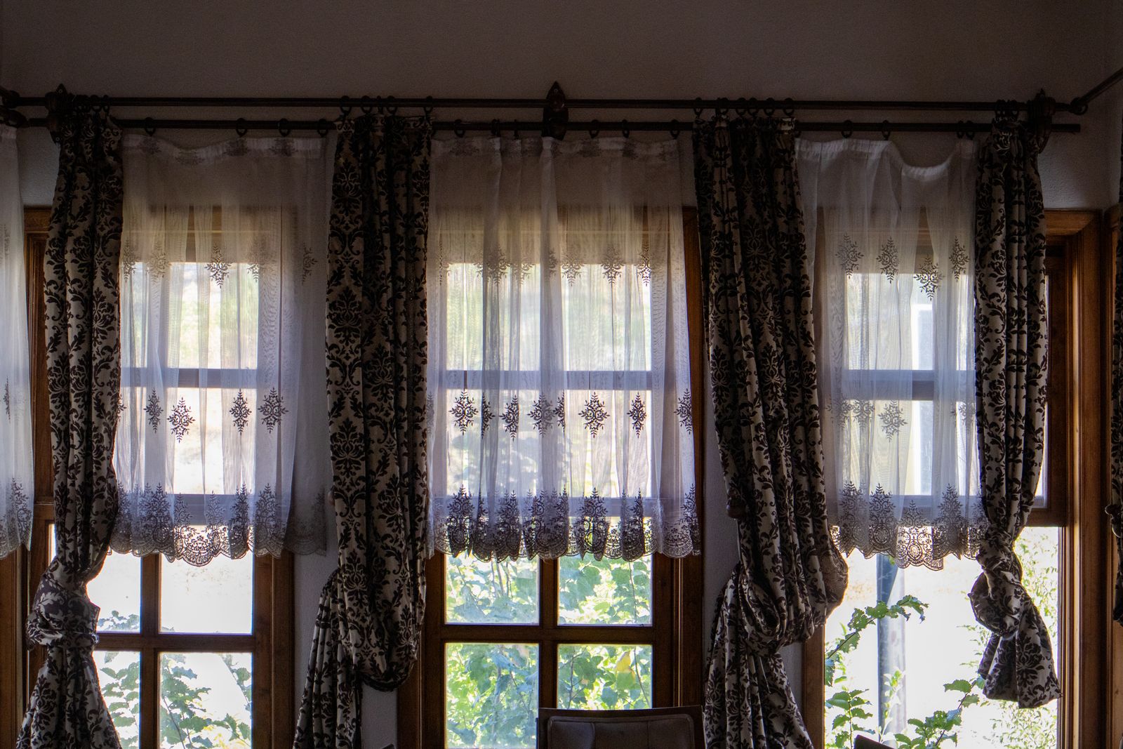 Layered custom draperies with sheer panels and decorative tie-backs